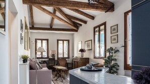 A cozy kitchen with wooden beams, a dining area with a table and chairs, and a living room with a sofa and a lamp. - Three Terraces (Venice)