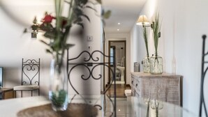 A modern interior with a glass table, metal chair, and decorative vases.