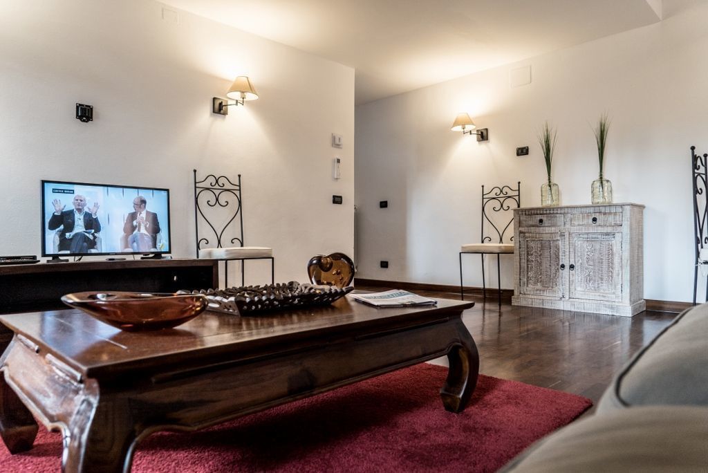 A living room with a wooden coffee table, a red rug, a television, and a white cabinet with decorative items.