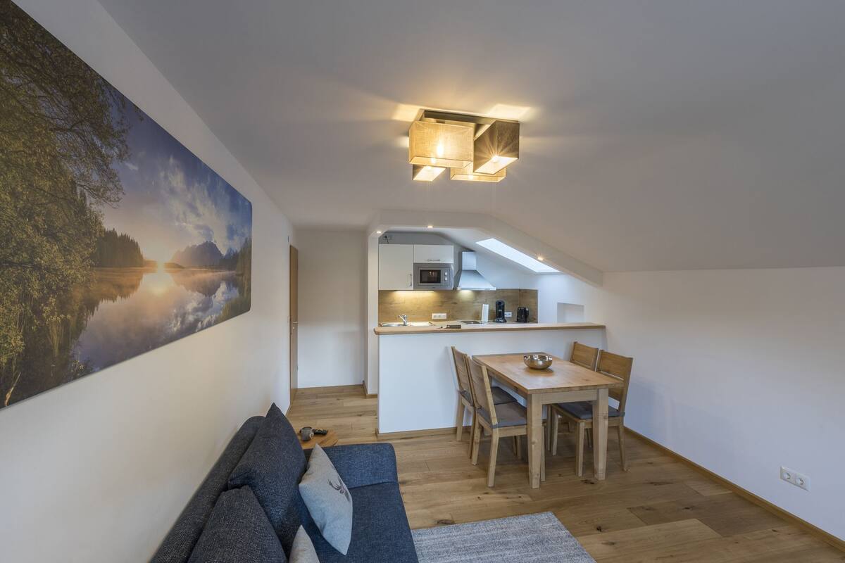 A modern loft apartment with a dining area, kitchen, and a large painting of a landscape.