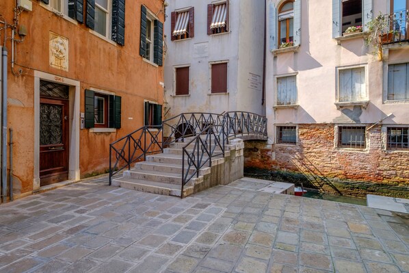 A narrow stone-paved street with a staircase leading to a building entrance.