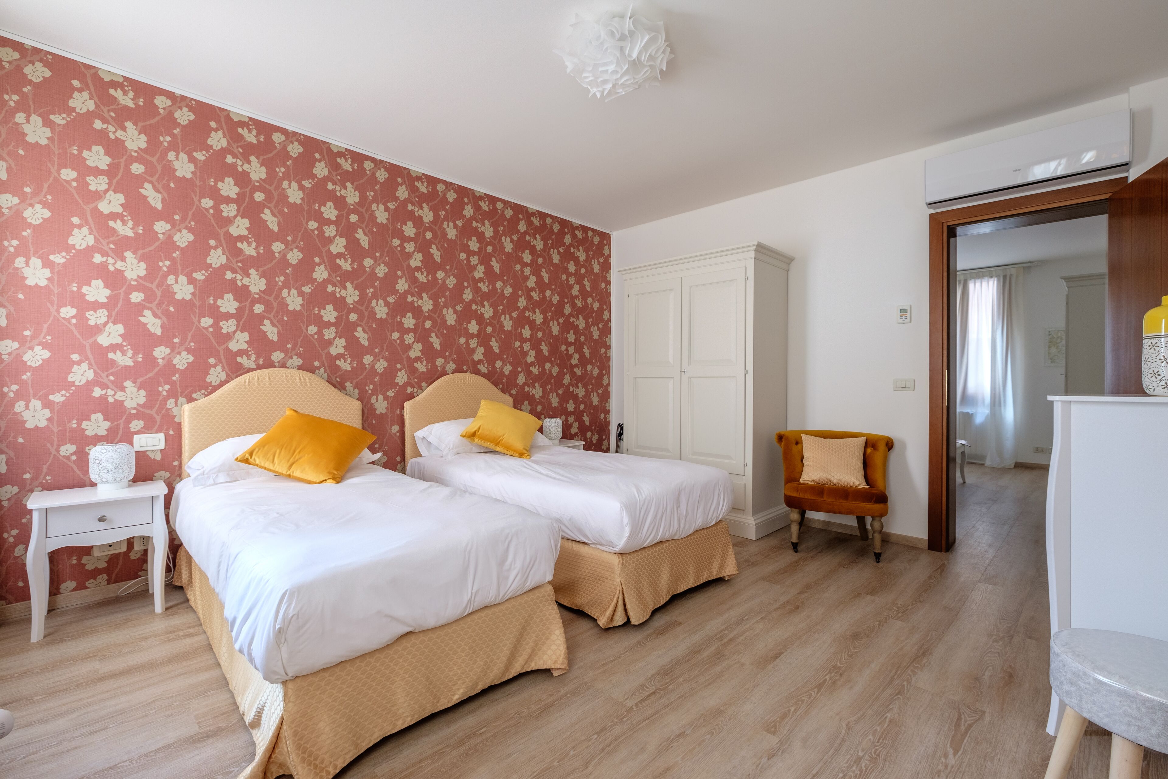 A hotel room with two beds, a wardrobe, a chair, and a desk.