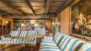 Ein geräumiges Wohnzimmer mit gestreiften Sofas, einem großen Bücherregal und einem klassischen Gemälde.