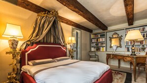 Ein stilvoll eingerichtetes Schlafzimmer mit einem großen Bett, einem verzierten Kopfteil und einem klassischen Chandelier.