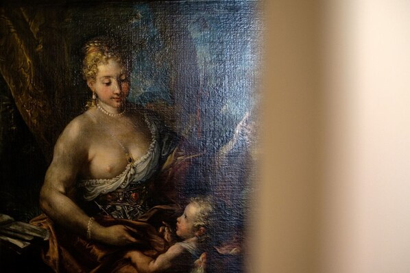 A classical painting with a central figure seated, surrounded by drapery and a dark background.