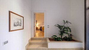 A hallway with a framed picture, a staircase, and a potted plant. - Guarana (Venice)