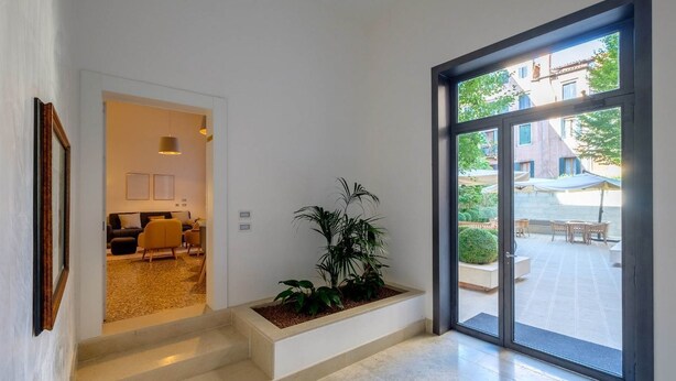 A modern interior with a staircase leading to a living area, a large window with a view of the outside, and a potted plant. - Guarana (Venice)