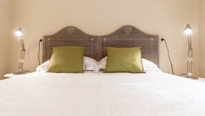 A bed with a wooden headboard, two green pillows, and two bedside lamps. - Kandinskij House (Venice)