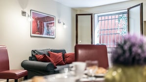 A modern living room with a grey sofa, red cushions, a framed artwork, and a window with metal bars. - Kandinskij House (Venice)