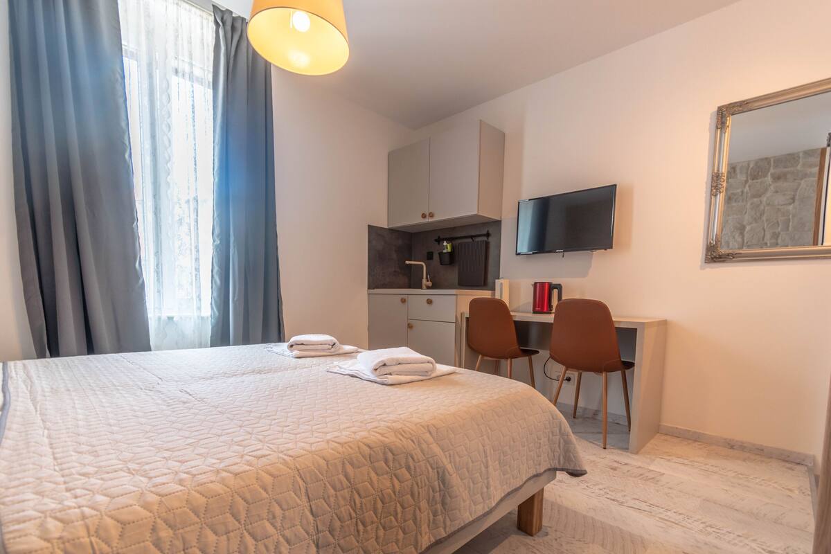Een hotelkamer met een bed, een bureau, een stoel, een televisie en een spiegel.