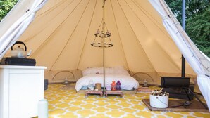 A tent with a bed, a hanging light fixture, a stove, and a small table with items on it. - Baby Moon (Guisborough)