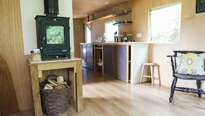 A cozy cabin interior with a wood-burning stove, a kitchen area, and a dining space. - Baby Moon (Guisborough)