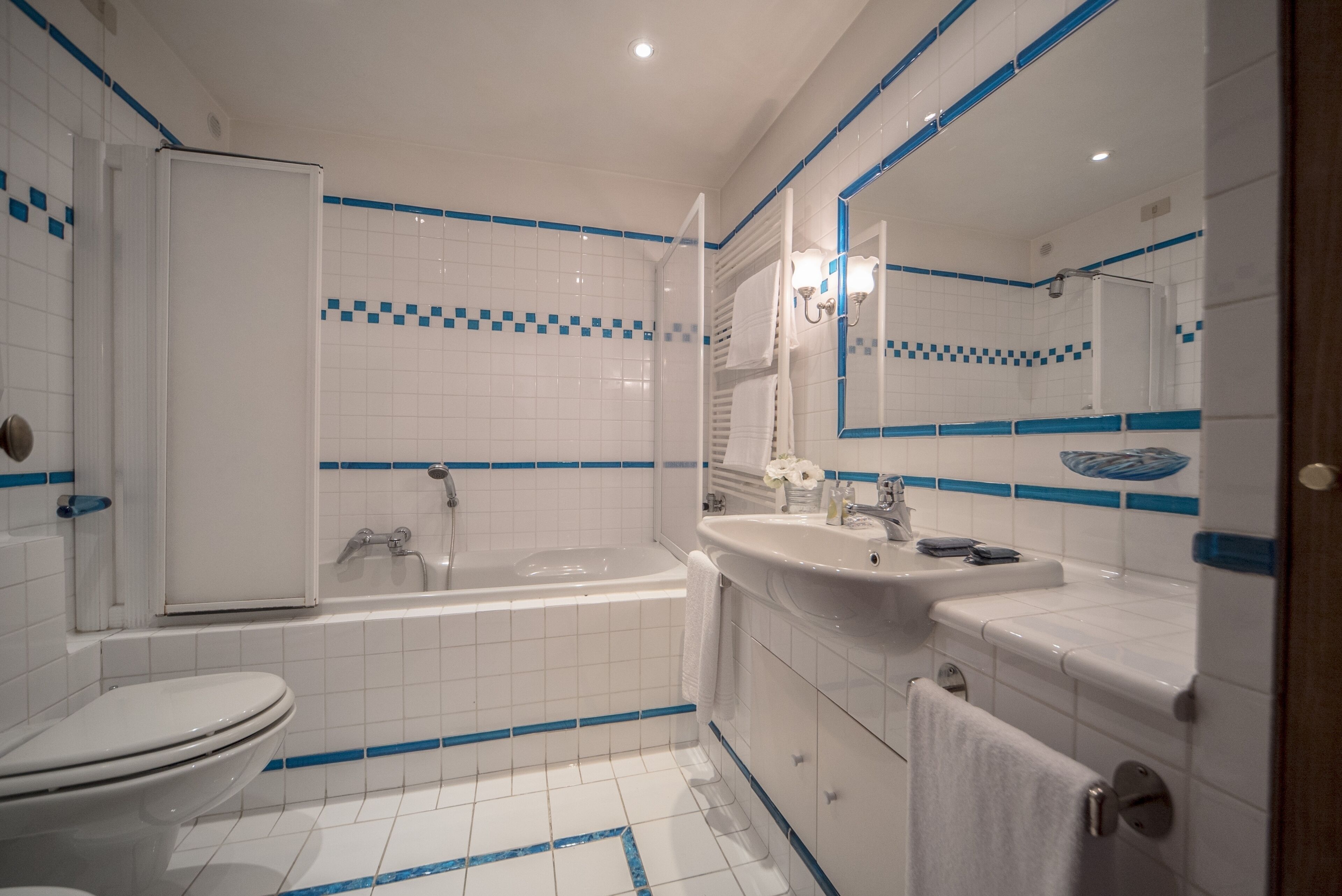 A modern bathroom with a toilet, bathtub, and two sinks.