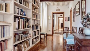 Una biblioteca con estanterías, suelo de madera y un comedor con sillas y una mesa.