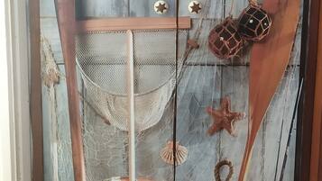 Une pièce décorée sur le thème de la marine, avec une porte en bois, une bouée de sauvetage, une lanterne et divers objets de décoration maritimes.