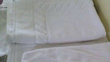 Toallas blancas dobladas con cuidado apiladas sobre una cama.