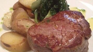 Une assiette contenant un steak cuit, des pommes de terre et des légumes verts.