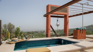 Ein Pool auf dem Dach mit freiem Blick auf die Stadtlandschaft, einer hängenden Leuchte und einem Backsteinbau mit Wasserspiel.