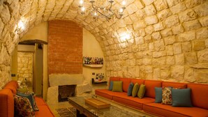 Ein gemütliches Wohnzimmer mit Steinwand, Kamin aus Backsteinen, einem roten Sofa und einem Glastisch.