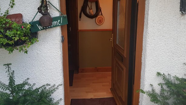 A wooden door with a glass panel, a welcome sign, and a wall-mounted hat. - Hosefield Bed and Breakfast (Ellon)