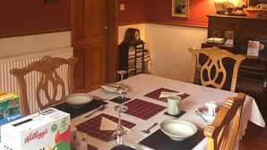 A dining room with a table set for two, featuring a box of Kellogg's Corn Flakes cereal, a clock, and a lamp. - Hosefield Bed and Breakfast (Ellon)