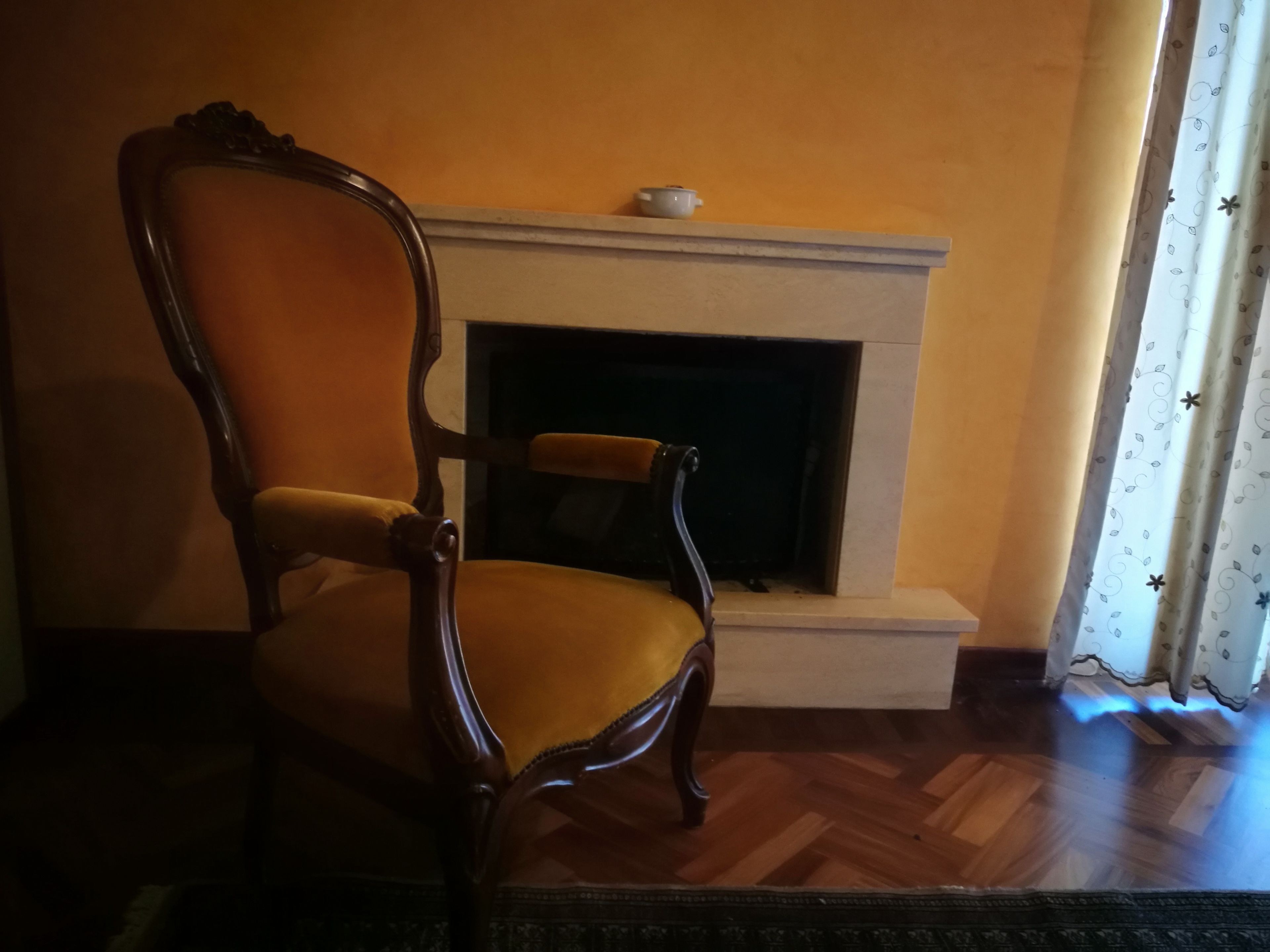 Een kamer met een houten stoel, een open haard en een kamer met een patroon.