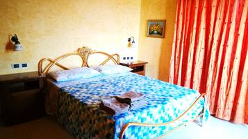 A bedroom with a bed, nightstands, a wall-mounted lamp, and a painting.