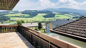 A balcony with a view of green fields and distant mountains. - Residence Privée - Spielberg Obdach (Obdach)