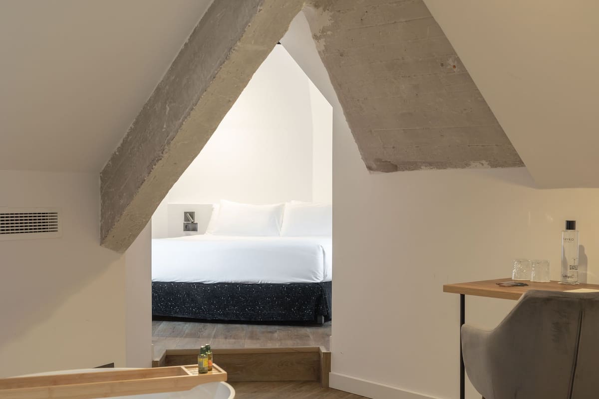 A bedroom with a bed, a desk, and a chair.