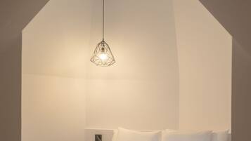 Un dormitorio moderno con una cama grande, una lámpara colgante geométrica y suelo de madera.
