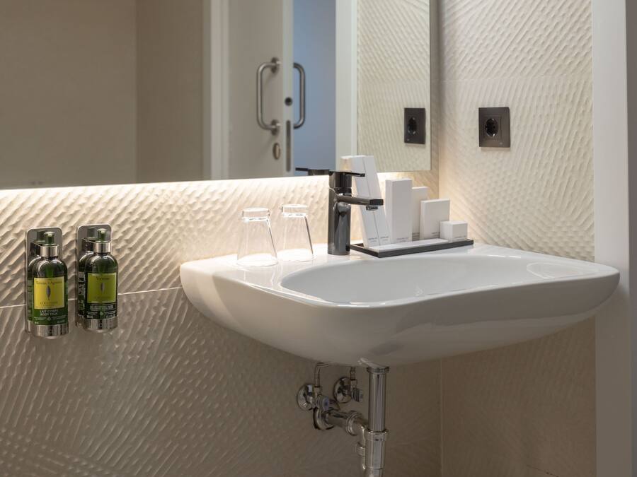 Ein Badezimmer mit einem weißen Waschbecken, zwei Lotionflaschen und einem Spiegel.