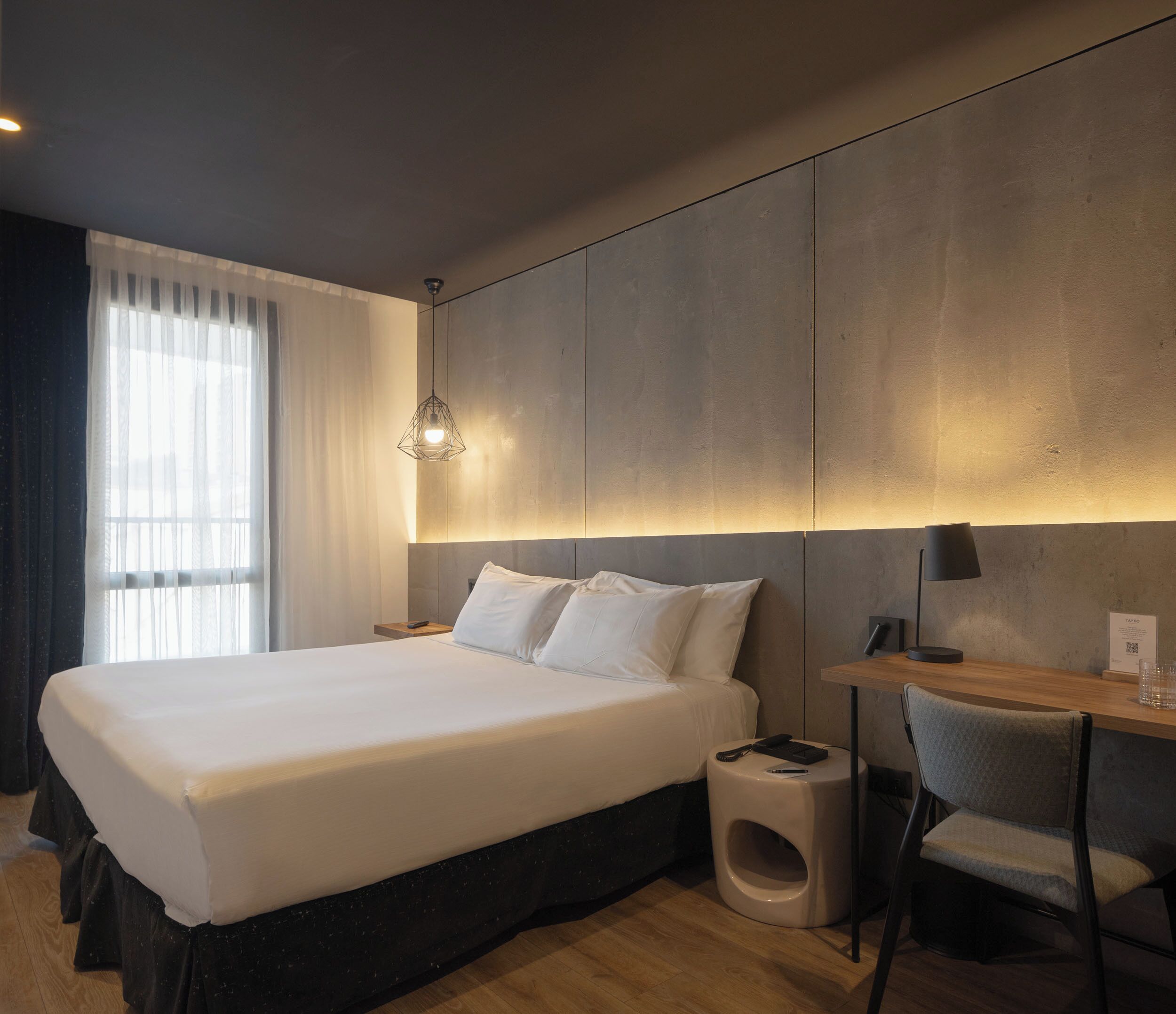 Una habitación de hotel moderna con una cama grande, un escritorio y una silla.