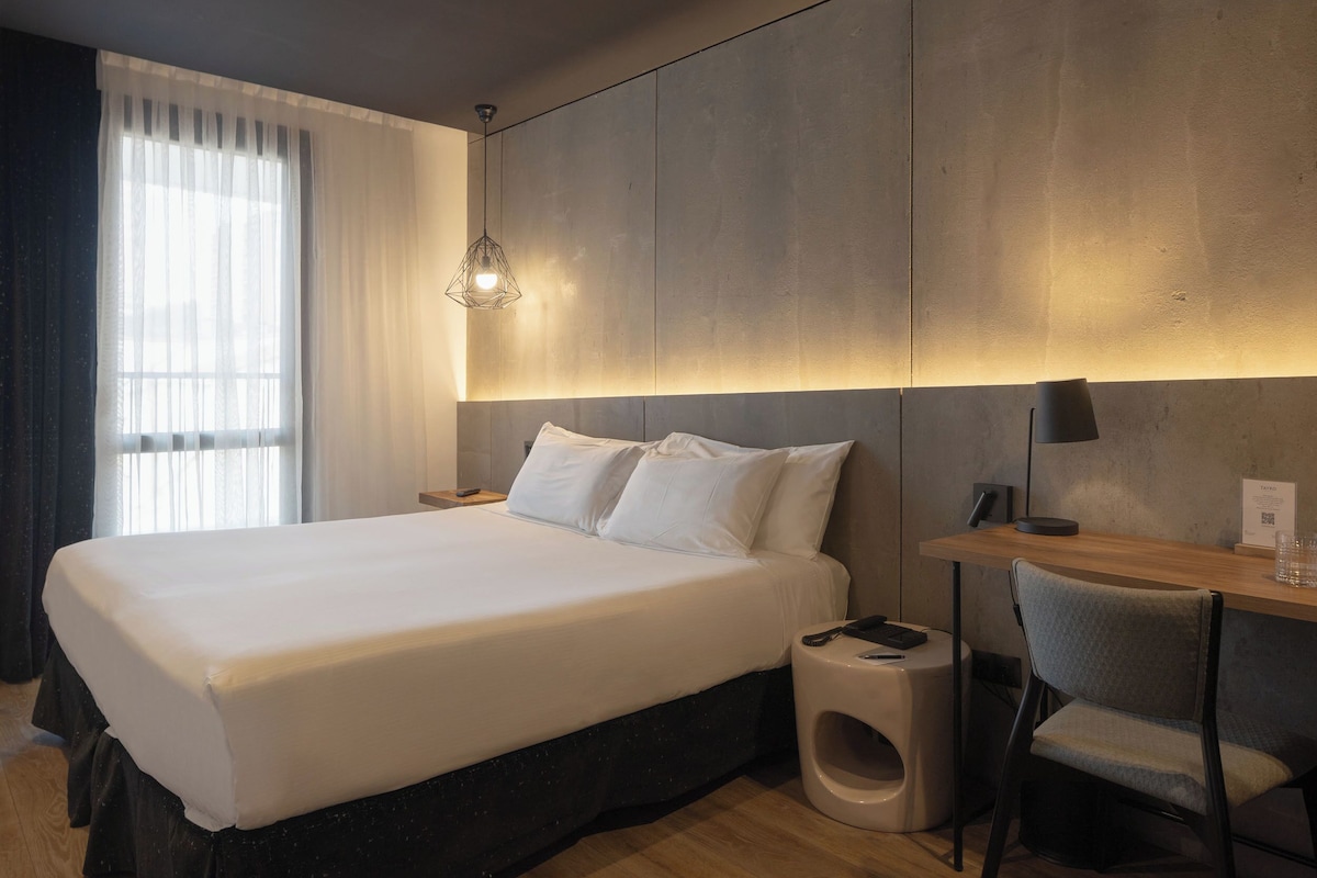 Une chambre d’hôtel moderne avec un grand lit, un bureau et une chaise.