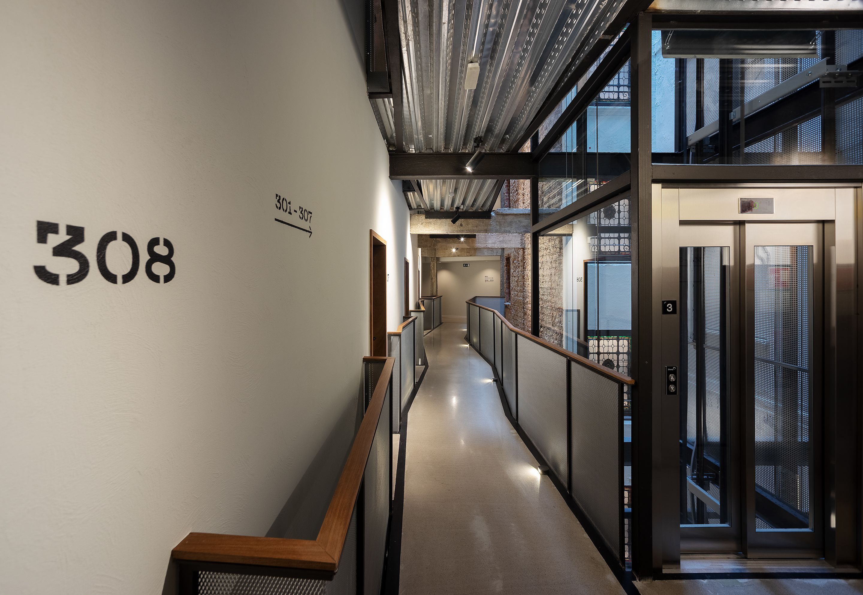 Un pasillo moderno con el número '308' en la pared, una escalera y un ascensor.