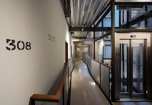 A modern hallway with a number '308' on the wall, a staircase, and an elevator. - Hotel Tayko Bilbao (Bilbao)