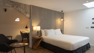 Una habitación de hotel moderna con una cama grande, un escritorio con una silla y una mesita.