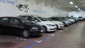 Fila de coches aparcados en un garaje de hotel, con señales que indican plazas reservadas para el Hotel Tayko.