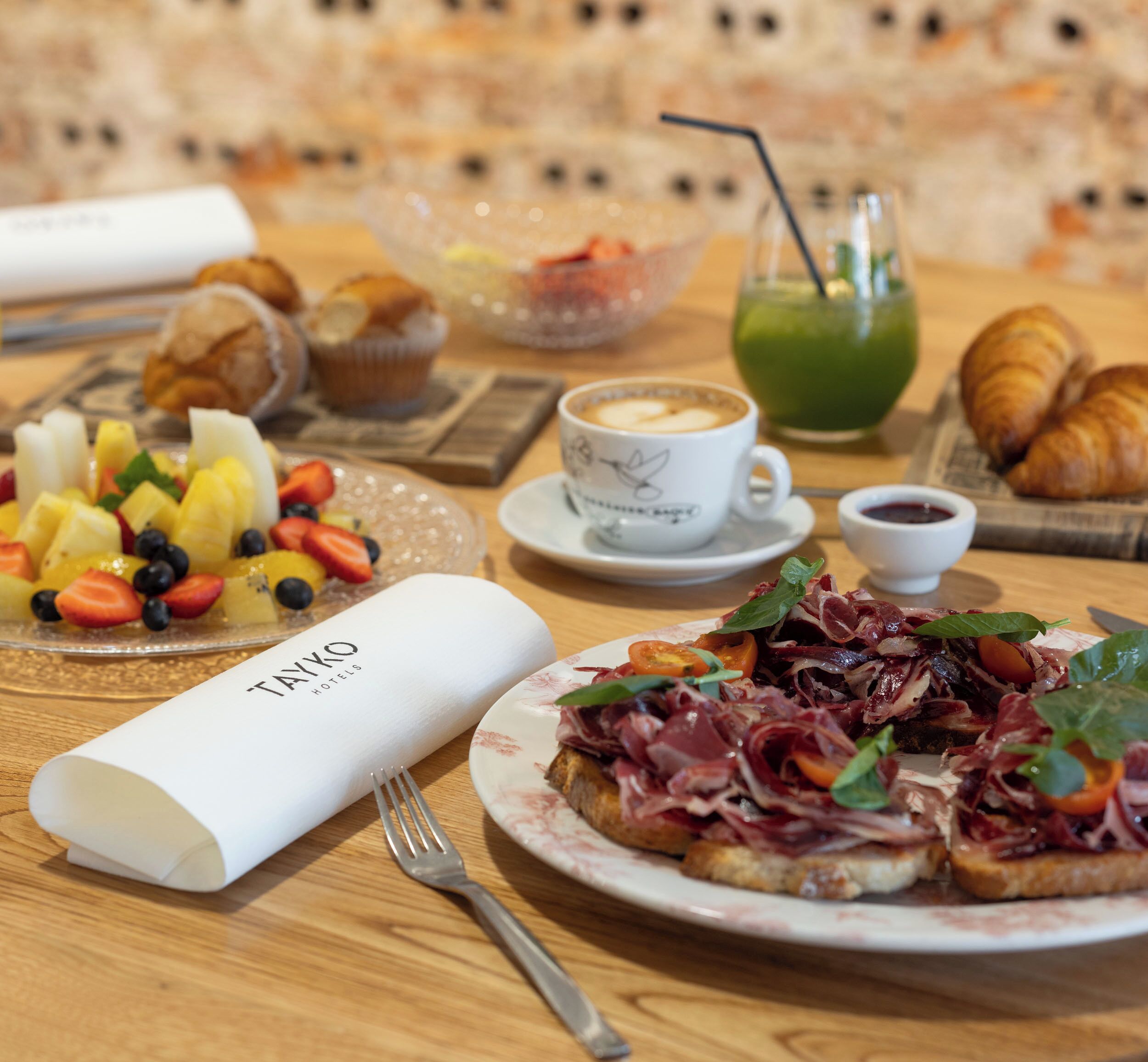 A breakfast setting with croissants, fruit, coffee, and a menu.
