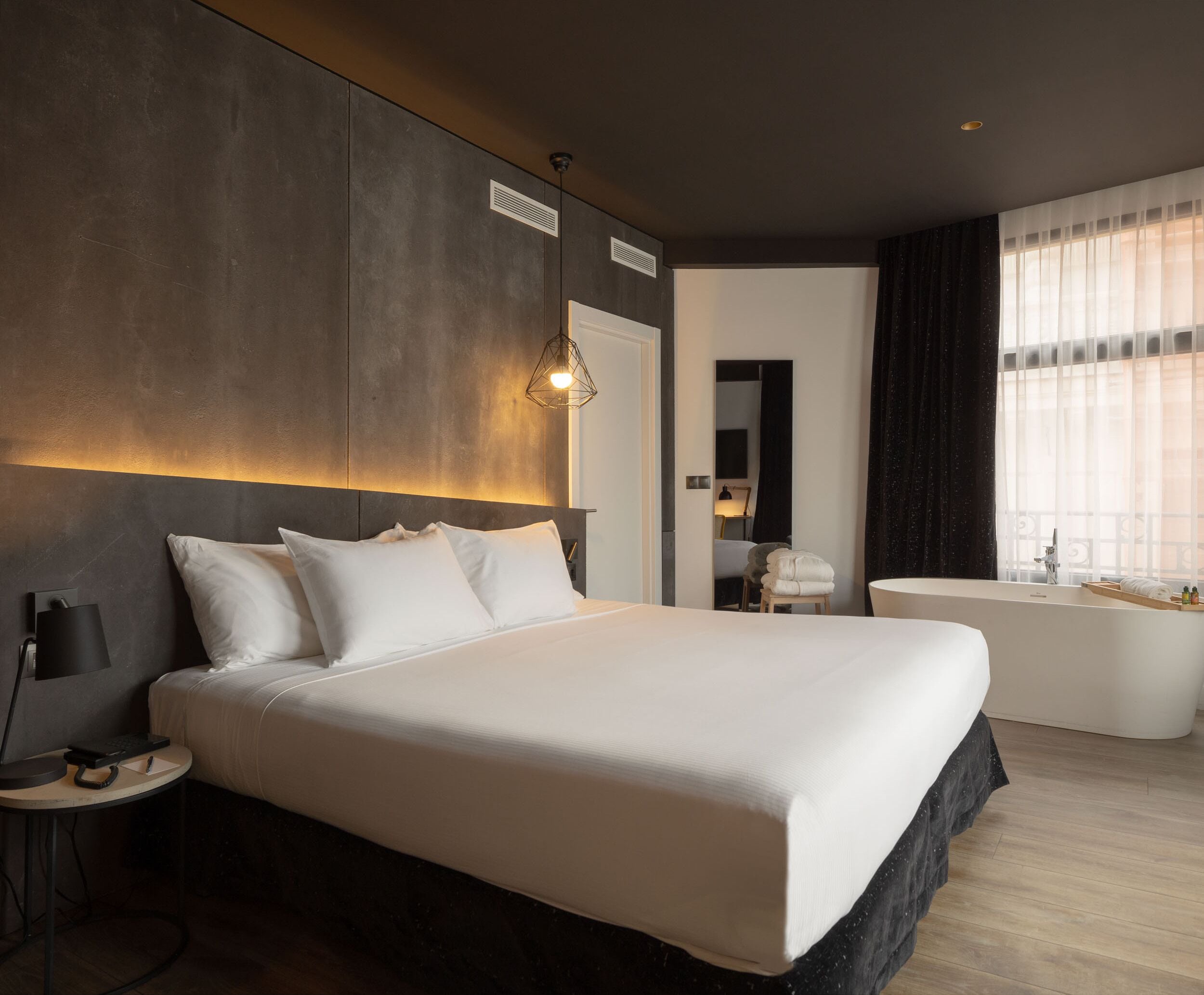Una habitación de hotel moderna con una cama grande, baño privado y vistas a la ciudad.