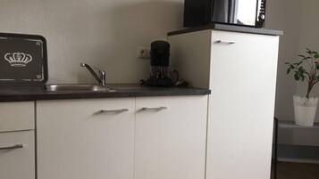 A compact kitchen with a microwave, coffee maker, and a sink.