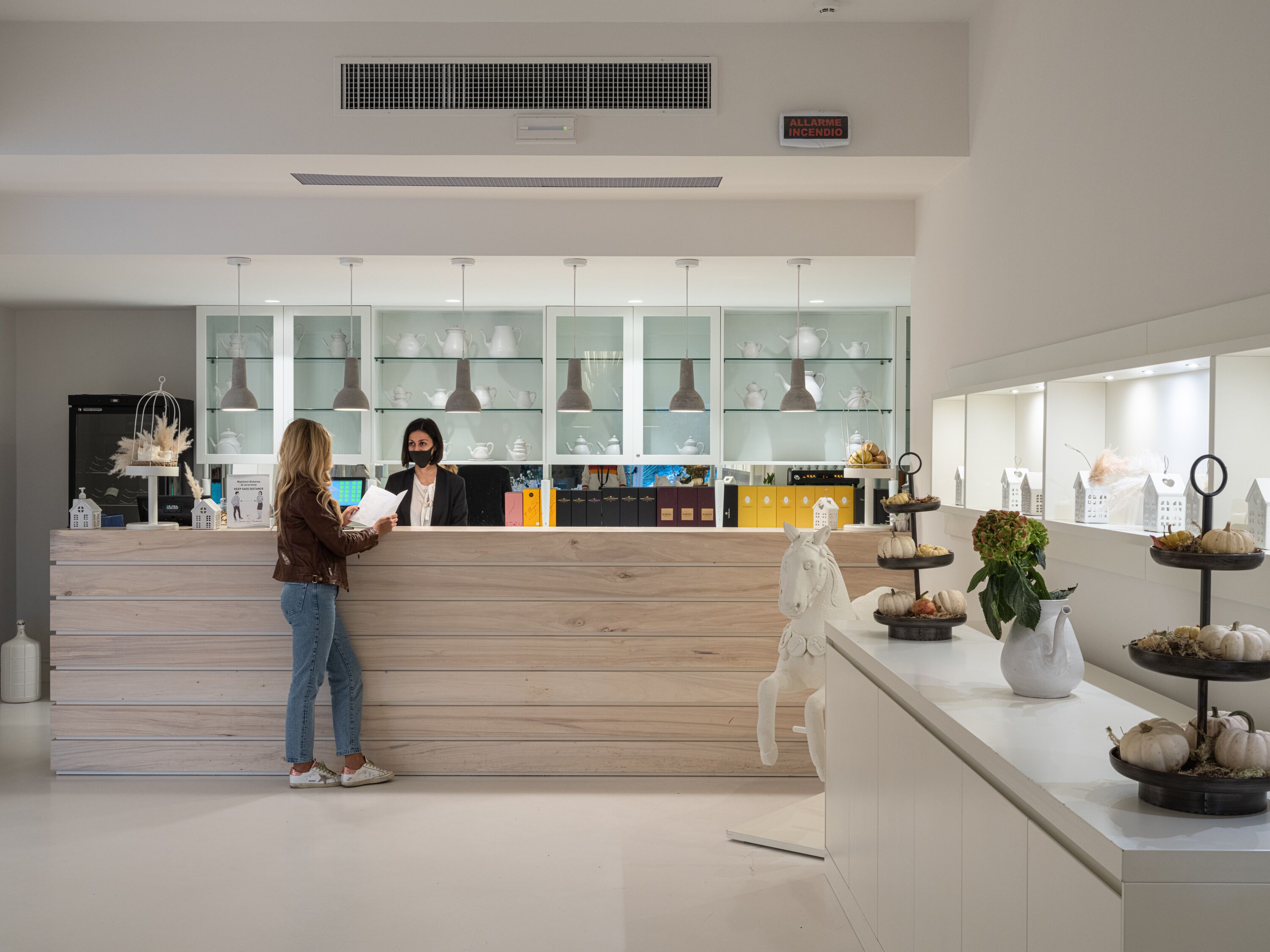 Een modern interieur met een receptiebalie, een theepottenpresentatie en een decoratief paardbeeld.