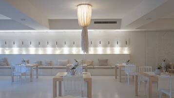 Un comedor moderno con mobiliario blanco, una lámpara central y una exhibición de luces en la pared.