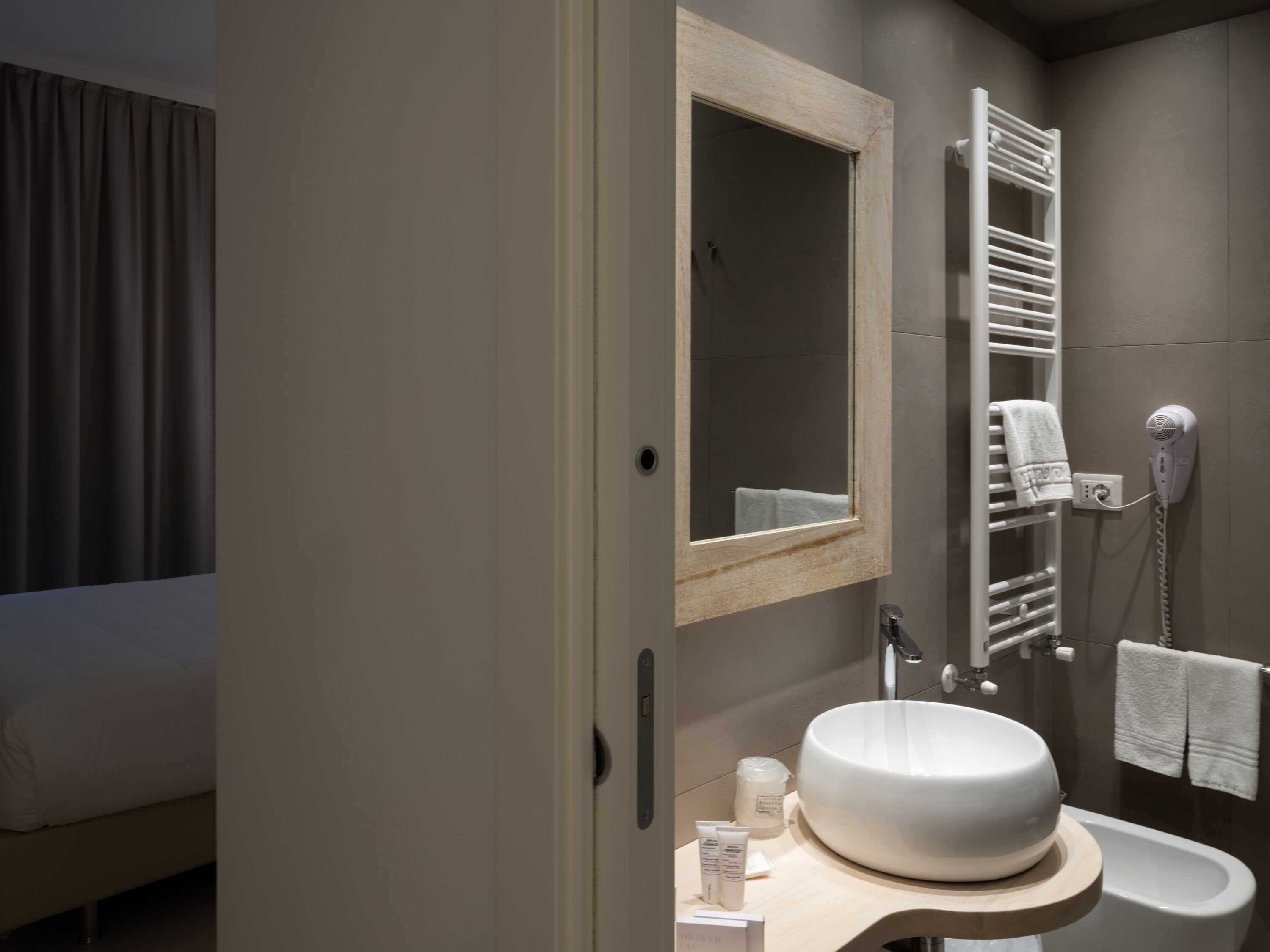 A modern bathroom with a large mirror, a built-in sink, a towel rack, and a hairdryer.