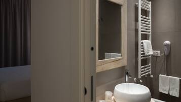 A modern bathroom with a large mirror, a built-in sink, a towel rack, and a hairdryer.