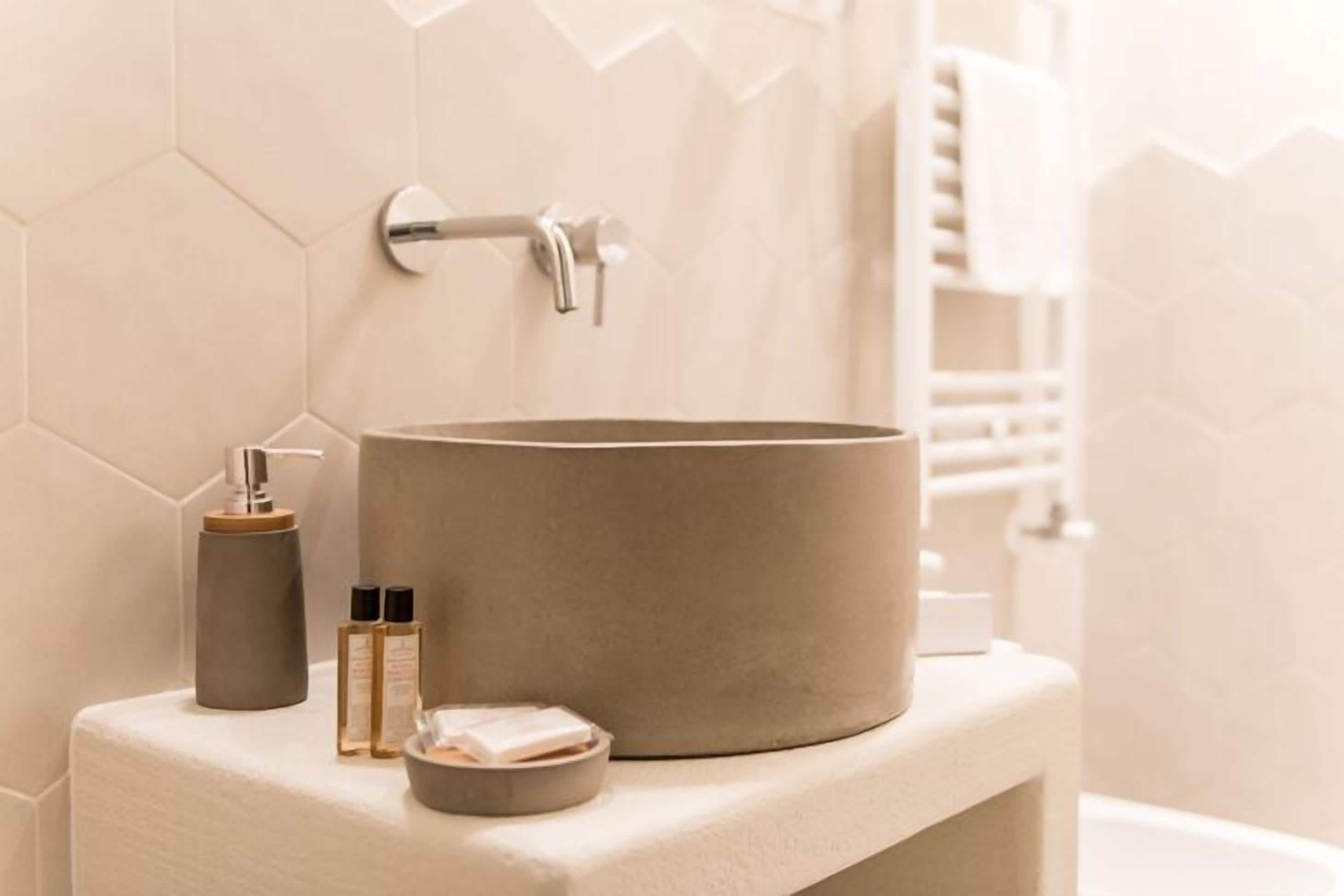 A bathroom with a beige sink, a towel, and a soap dispenser on a white countertop.