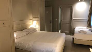 Una camera d'albergo con un letto grande, un letto più piccolo, un armadio e una porta.