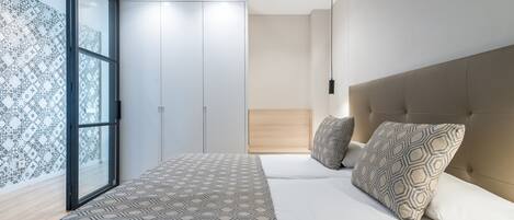Un dormitorio moderno con una cama grande, ropa de cama estampada, un cabecero y un ventanal con cortinas estampadas.