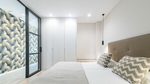 A bedroom with a bed, pillows, a wardrobe, and a sliding glass door.