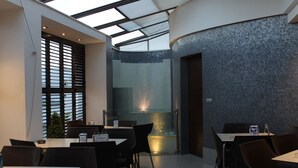 A modern restaurant with a high ceiling and skylight, featuring dark tiled walls and black chairs. - Pensión Restaurante Casablanca (Torreperogil)