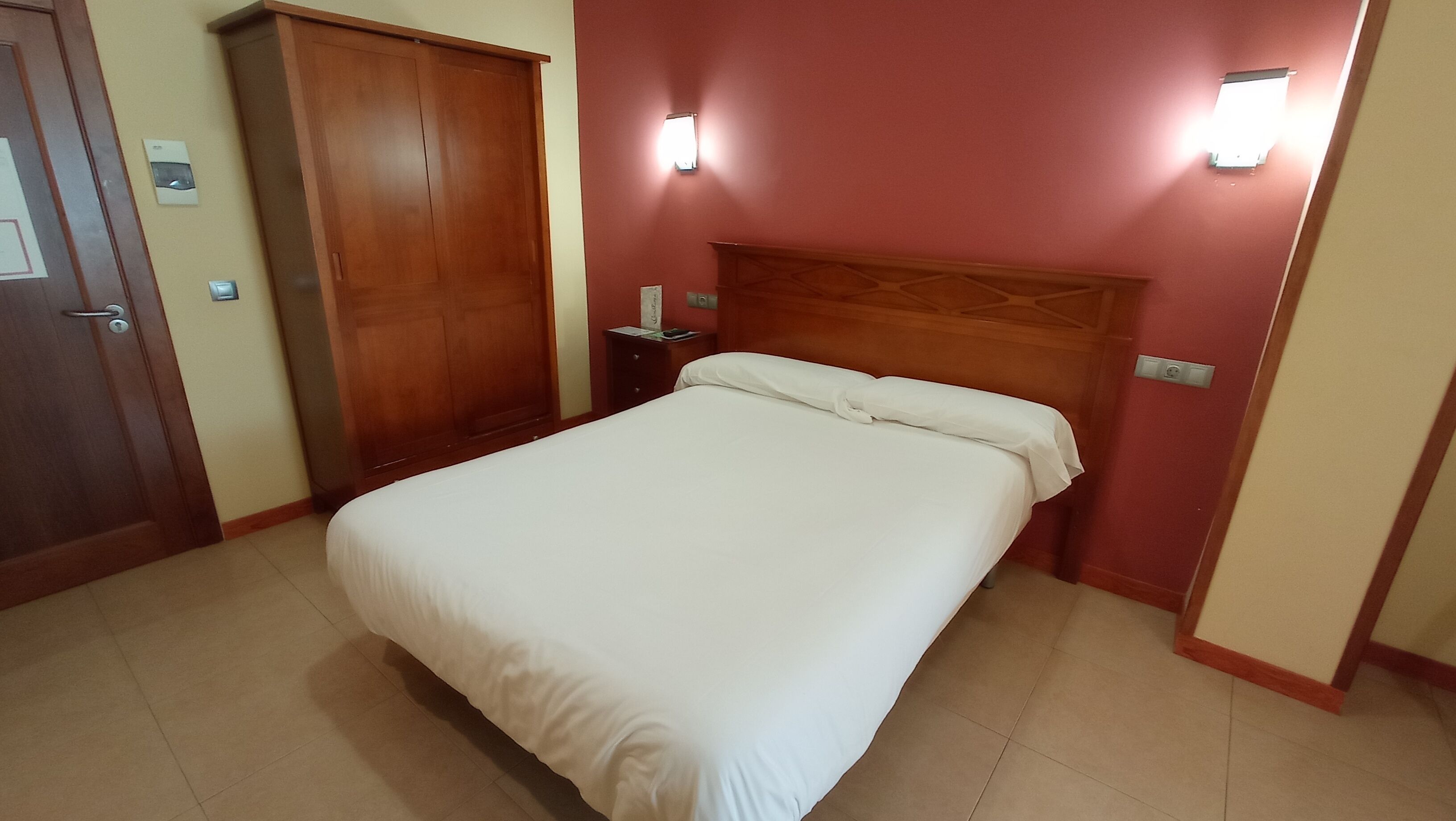 Une chambre à coucher avec un lit, une armoire en bois et des tables de chevet.